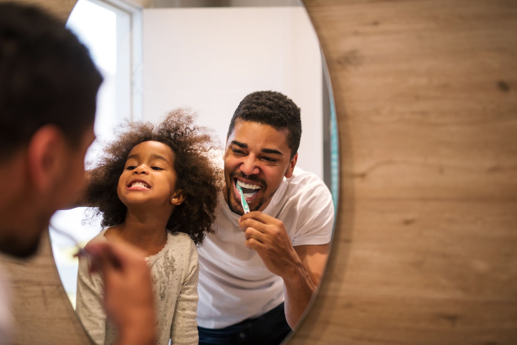 father and daughter brushing their teeth